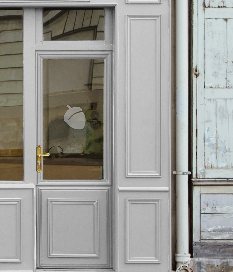An image of a grey door with a glass panel, a brass handle and grey blue acorn ici logo