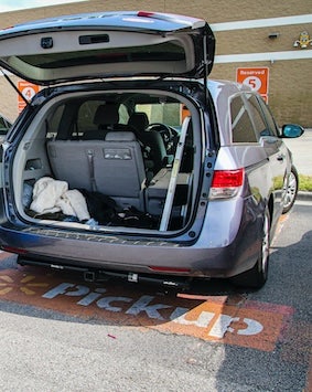 Open trunk of a car parked in a designated 'Curbside Pickup' spot at a store, indicating convenience for loading purchases.