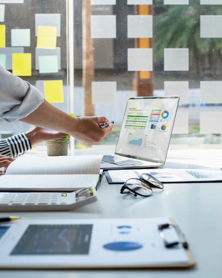 Professional presenting data charts on laptop in a modern office.