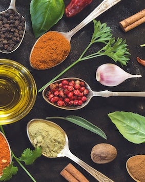 Various spices and herbs displayed on spoons, suggesting cooking ingredients.