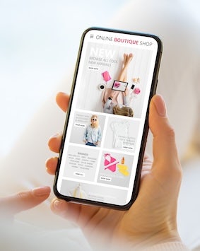 Hand holding smartphone displaying online boutique shop interface.